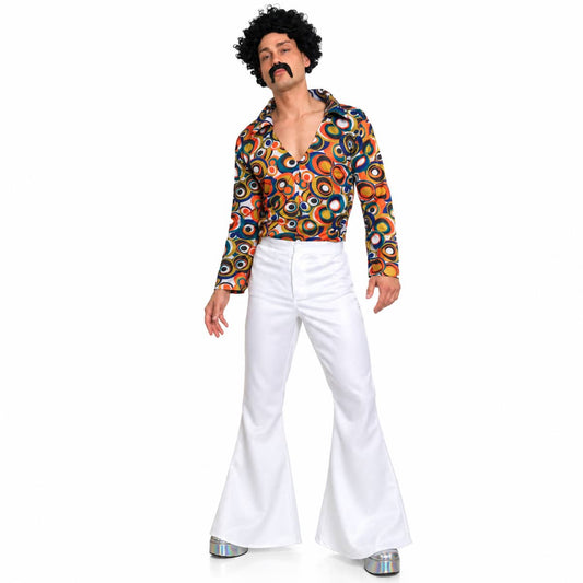 A man modeling a 1960s-style costume outfit consisting of a long-sleeve button-up shirt with a colorful retro circular pattern, white flared pants, and silver shoes, against a plain white background.